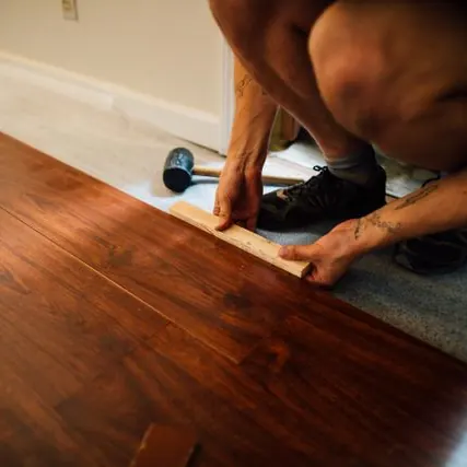 Instalação de piso laminado com martelo de borracha e espaçador